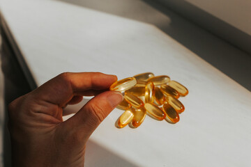 Woman's hand holds omega-3 in the sun's rays. Natural fish oil close-up
