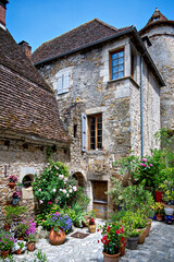 Lush floral decorations on a square with old stone houses in the village of Carennac in the region of Perigord, France