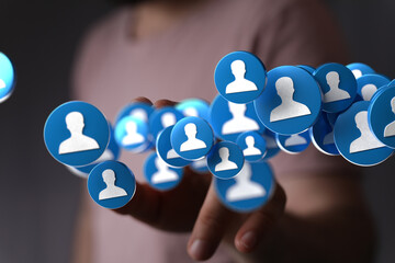 Person's hand interacts with digital profile icons, representing social media, networking, or...