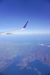 Airplane wing above the clouds during flight, view from airplane window.