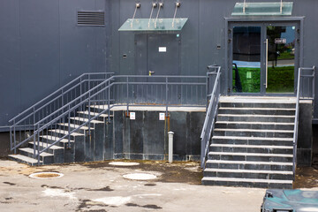 A tall black building features stairs that lead up to its entrance