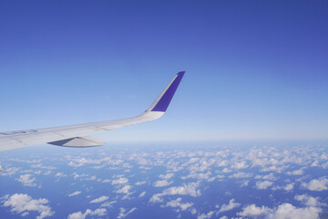 Obraz premium Airplane wing above the clouds during flight, view from airplane window.
