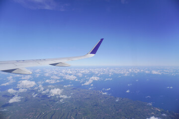Airplane wing above the clouds during flight, view from airplane window.