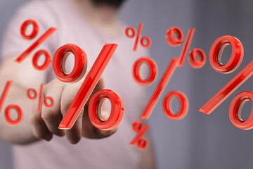 Red 3D percentage symbols floating around a person's hand, symbolizing discounts, interest rates,...