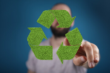 Eco-friendly concept. Man interacts with a digital recycling symbol made of grass.
