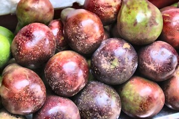 Close-up of Thai red-skinned avocado fruits stacked in a market stall