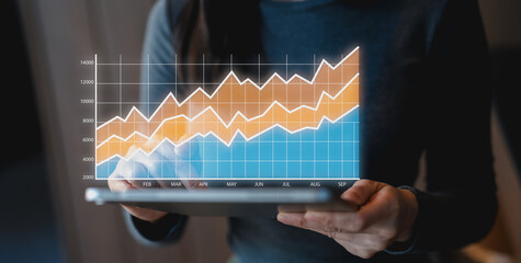 A person is analyzing a data chart on a tablet, showcasing a rising trend with different colored lines representing various metrics over time.