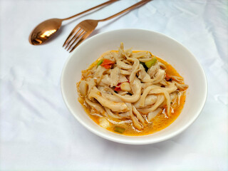 Selective focus. Stir-fried oyster mushrooms or tumis jamur tiram served with tomatoes to make the taste fresher and served on a white bowl with a white background. Spoon and fork.