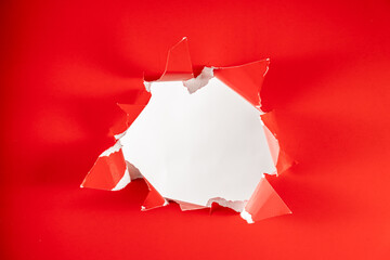 Photo of Solid red background ripped hole reviling white backdrop
