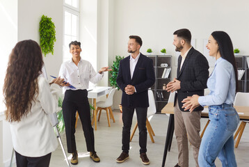 Portrait of a group of young confident business people standing in modern office discussing job...