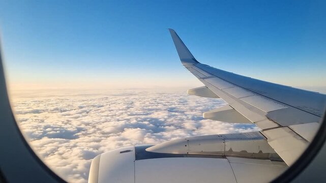 Aircraft wing  engine seen from plane window above clouds against a blue sky