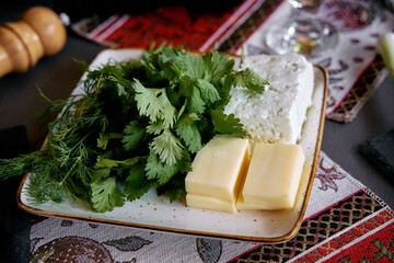 A Fresh Spread of Herbs and Cheese with Butter on a Decorative Plate, Perfect for Enhancing Your...