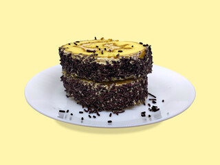 Chocolate sprinkled roll cake, covered with cream filling served on a white plate with a bright yellow background. Dessert event banner