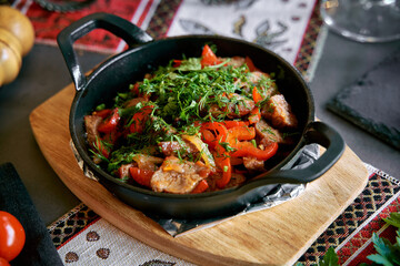 Sizzling Dish of Tender Meat and Vibrant Vegetables Garnished with Fresh Herbs Served in a Rustic Cast Iron Pan on a Wooden Board