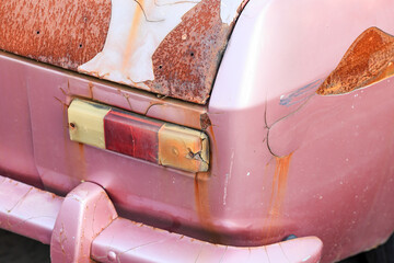 The car taillights of abandoned old rusty car on the side of the road.