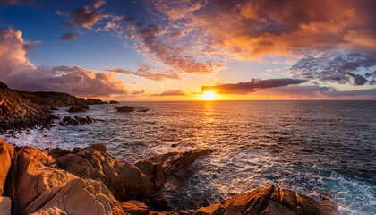 a breathtaking sunset over the ocean with fluffy clouds glowing in warm tones and a rocky shoreline