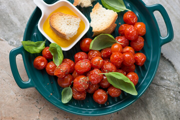 Green serving tray with roasted cherry tomatoes, ciabatta, olive oil and fresh basil, horizontal shot, middle close-up, high angle view