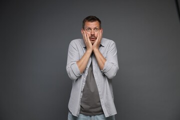 Man suffering from panic attack on grey background