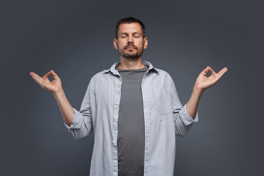 Panic attack. Man meditating to calm down on grey background