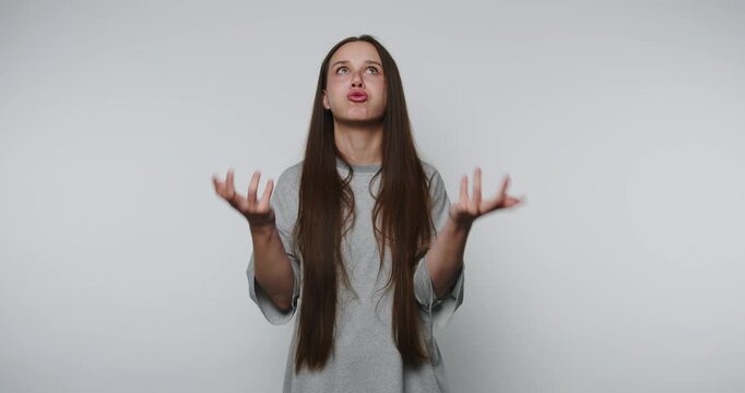 woman with long hair shows frustration, pouting with clenched fists, reflecting emotions of annoyance on white background