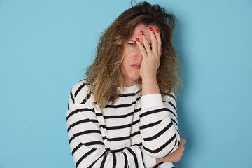 Woman suffering from hangover on light blue background