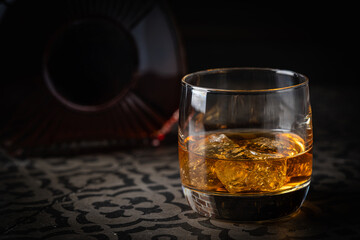 Whiskey with ice in glasses and bottle, dark background, copy space