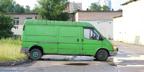 An old green rusty mini bus is parked in the yard near the lawn, Podvoyskogo Street, St. Petersburg, Russia, August 05, 2025