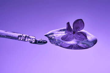 The texture of a serum with a dropper and a lilac flower.