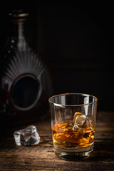 Whiskey with ice in glasses and bottle, dark background, copy space