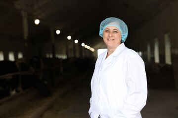 Portrait of veterinarian inside cowshed in dairy farm, space for text