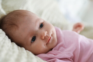 Cute newborn baby lying on bed indoors