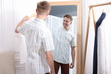Obraz premium Getting ready. Young man trying on clothes near mirror at home