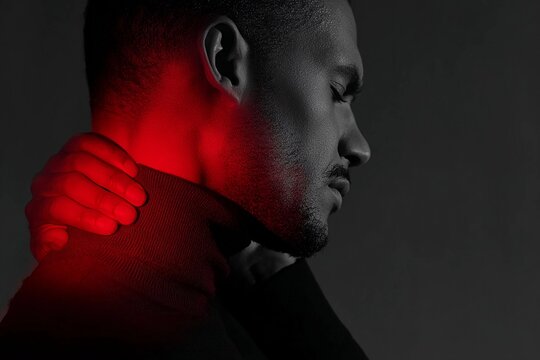 Man with thoughtful expression illuminated by red light in a dark setting