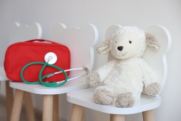 Pediatrician concept. Toy sheep, medical bag and stethoscope on chairs in clinic