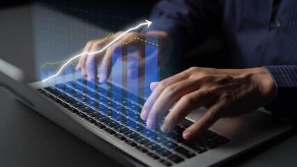A business professional analyzes data on a laptop with an upward trend chart displayed, signifying...