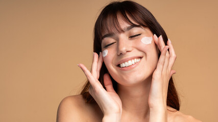 Beautiful young woman applying face luxury sunscreen or moisturizer cream for perfect hydrated...