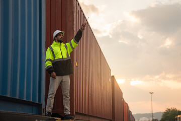 Foreman checking inventory or task details on freight train cars and shipping containers. Logistics...