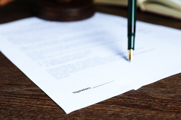 Signing notary document with fountain pen at wooden table, selective focus