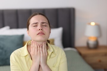 Young woman suffering from sore throat at home, space for text