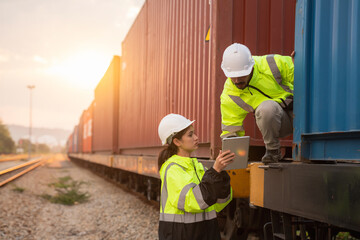 Foreman checking inventory or task details on freight train cars and shipping containers. Logistics...