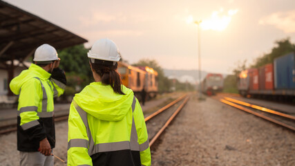 Foreman checking inventory or task details on freight train cars and shipping containers. Logistics...