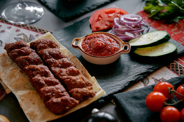 Luscious Platter Featuring Grilled Kebabs Accompanied by Fresh Vegetables and Rich Tomato Sauce on a Rustic Serving Board