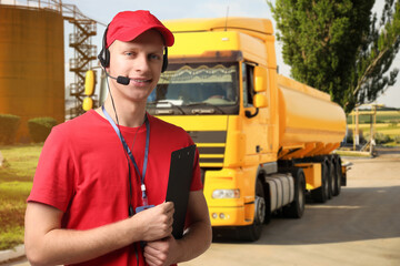 Car service worker with headset and clipboard against truck outdoors. Client support