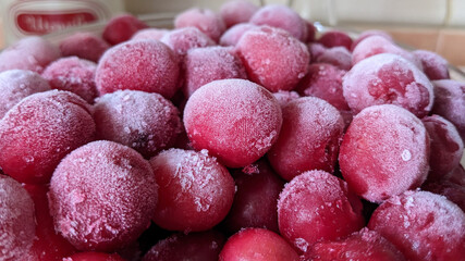 Close-up of frozen red plums covered in frost. Perfect for food storage or background texture.