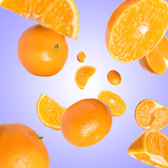 Sweet tangerines whirling in air against blue violet gradient background