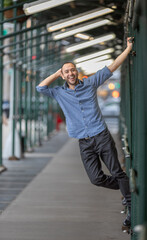 Hispanic Man Smiling Outdoors Beneath Urban Structure With a Playful and Relaxed Mood
