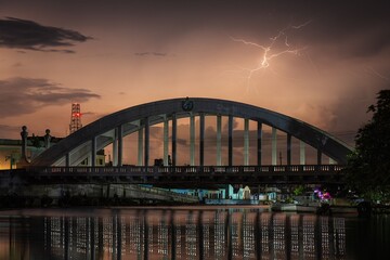 Night bridge with lightning and reflections.
