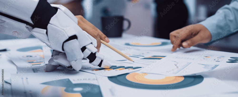 Poster a robotic hand engages with business charts and graphs on a table, symbolizing the blend of technolo