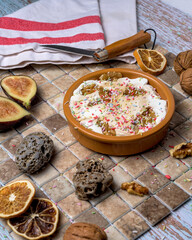 Autumnal dessert with walnuts, figs, and whipped cream, served in a rustic bowl. Seasonal dessert with colorful sprinkles on a ceramic tile background
