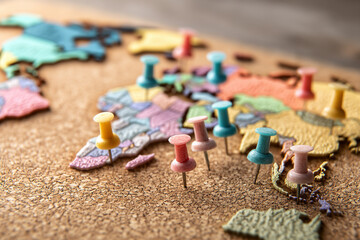 A global map made from colored thumbtacks pinned onto a corkboard, representing various connected travel destinations.